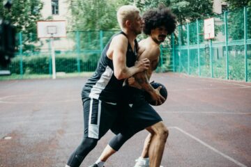 Two young men play basketball in an an outdoor court