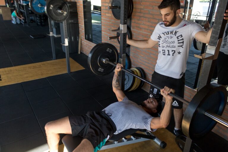 A man performs a bench press while his buddy watches