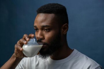 Young black man drinks a glass of milk