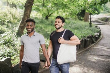 Happy gay couple walk holding hands in a park