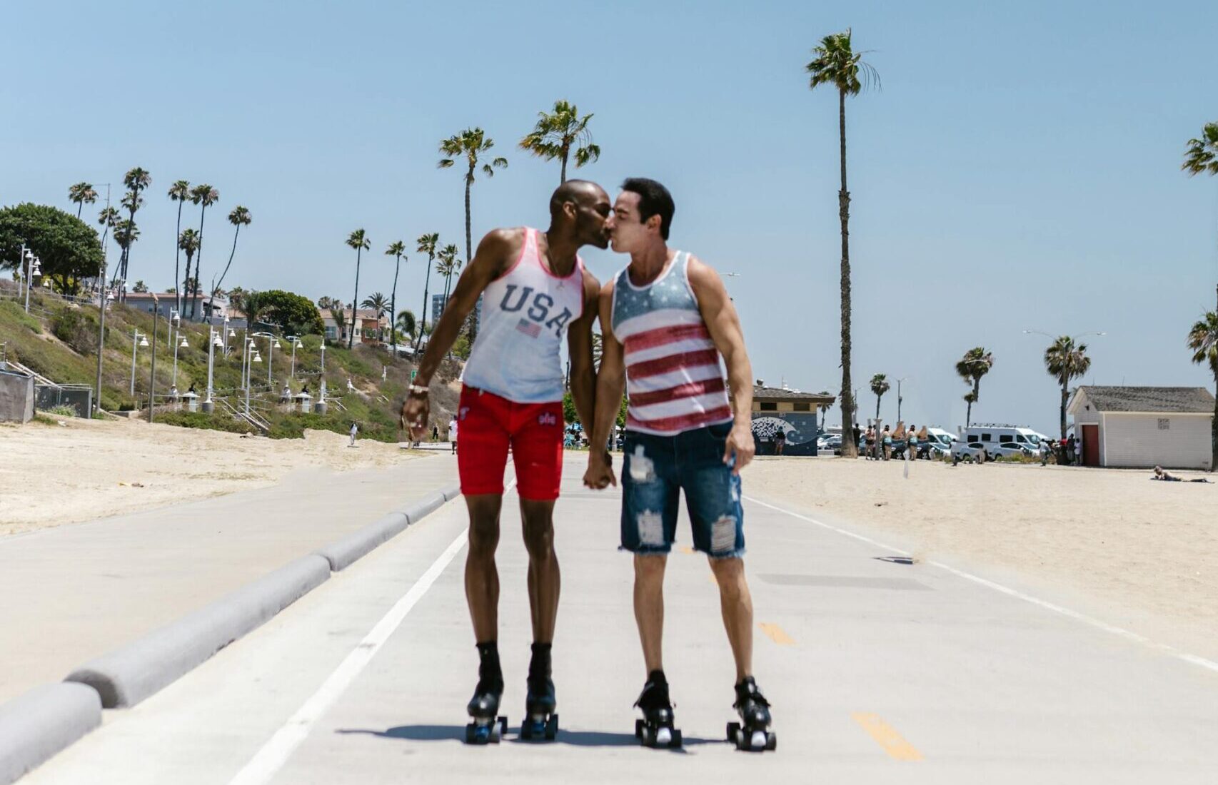 Happy gay couple kiss while rollerskating on a quiet street.