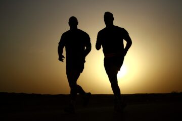 Two men jogging with the sun in the background