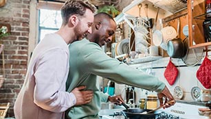 Affectionate gay couple prepare a meal in the kitchen