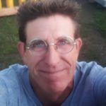 Man wearing glasses smiles in a selfie photo